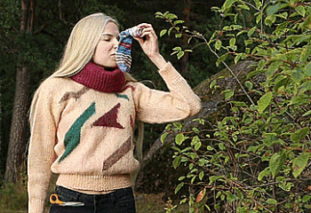 Blonde girl wearing jeans and a sweater gags herself in a forest